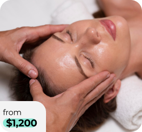 A woman lies with eyes closed while a spa therapist gently massages her temples with both hands, suggesting a facial treatment, with a 'from $1,200' price tag overlay in the bottom-left corner.